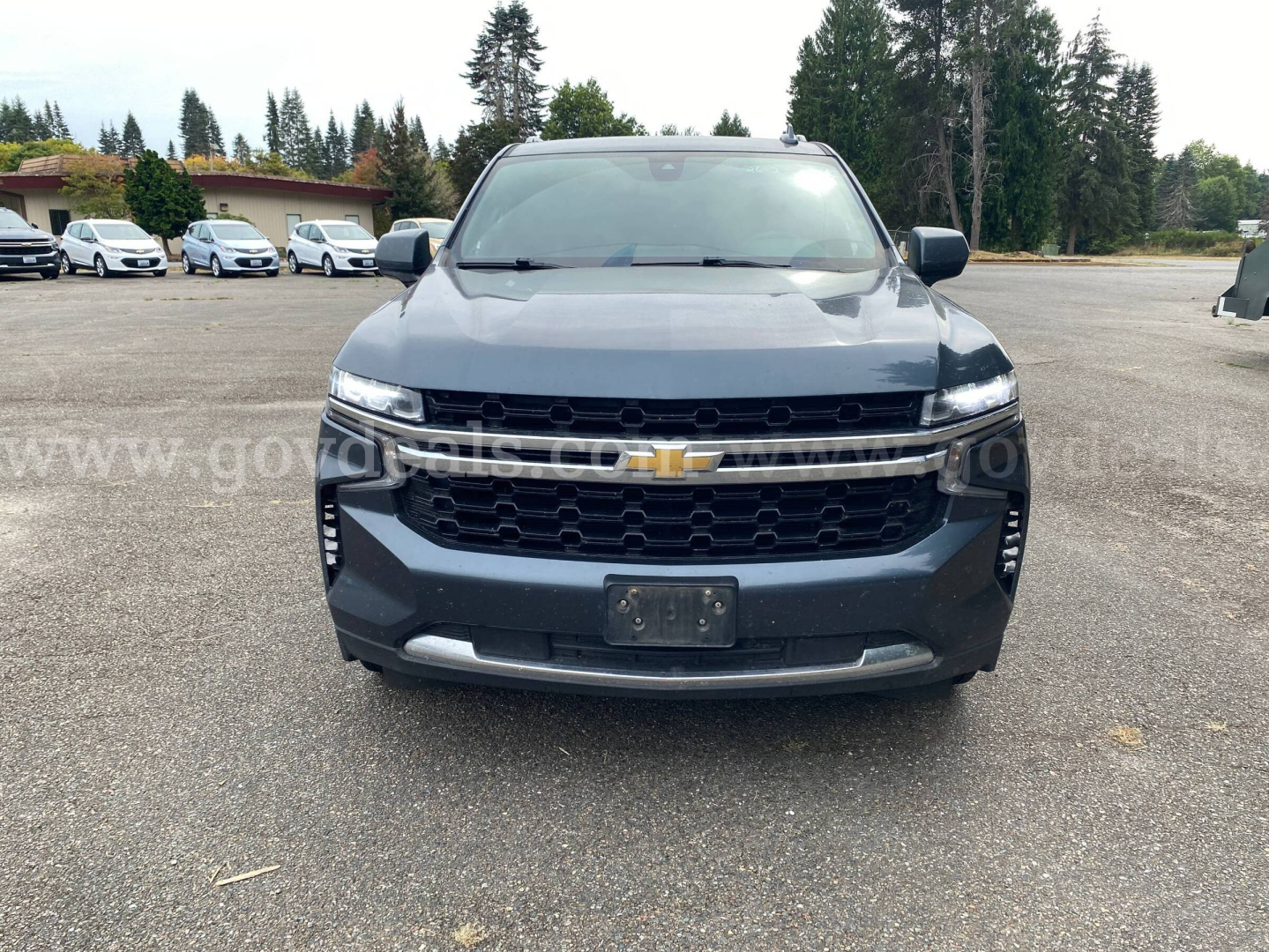 Front view of a dark blue 2021 Chevrolet Suburban with Chevrolet emblem, grille, headlights, and bumper in clear view.