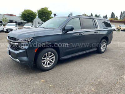 2021 Chevrolet Suburban SUV in a dealership lot showing front left side, chrome grille, LED headlights, side steps, tinted windows, and alloy wheels.