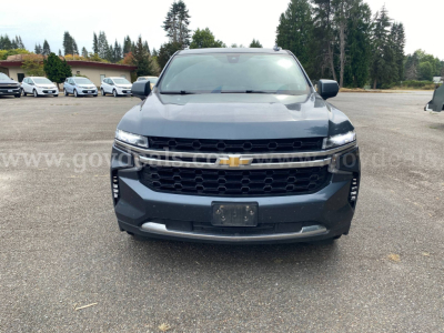 Front view of a dark blue 2021 Chevrolet Suburban with Chevrolet emblem, grille, headlights, and bumper in clear view.