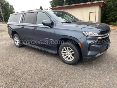 Chevrolet Suburban 2021 SUV in blue-gray with extended cargo area, side view showing front grille and headlights.