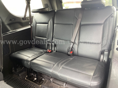 Chevrolet Suburban rear seat area with black leather seating and seat belts visible.