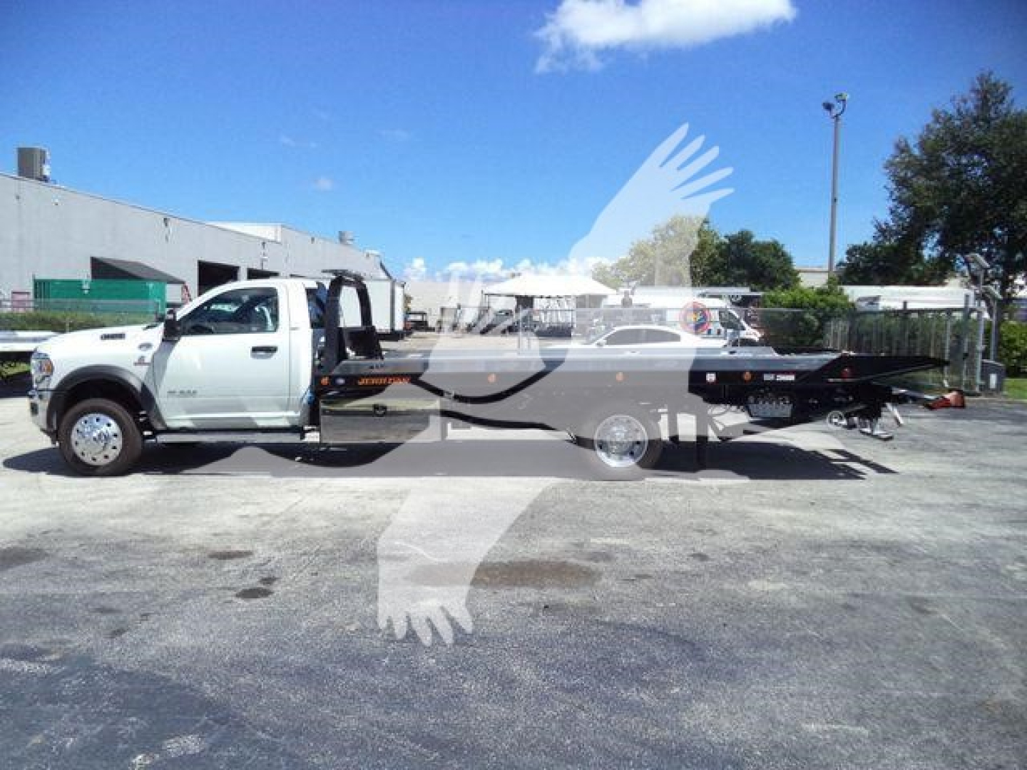 2024 Ram 5500 SLT truck with rollback equipment, side view, showing a long flatbed and towing setup.