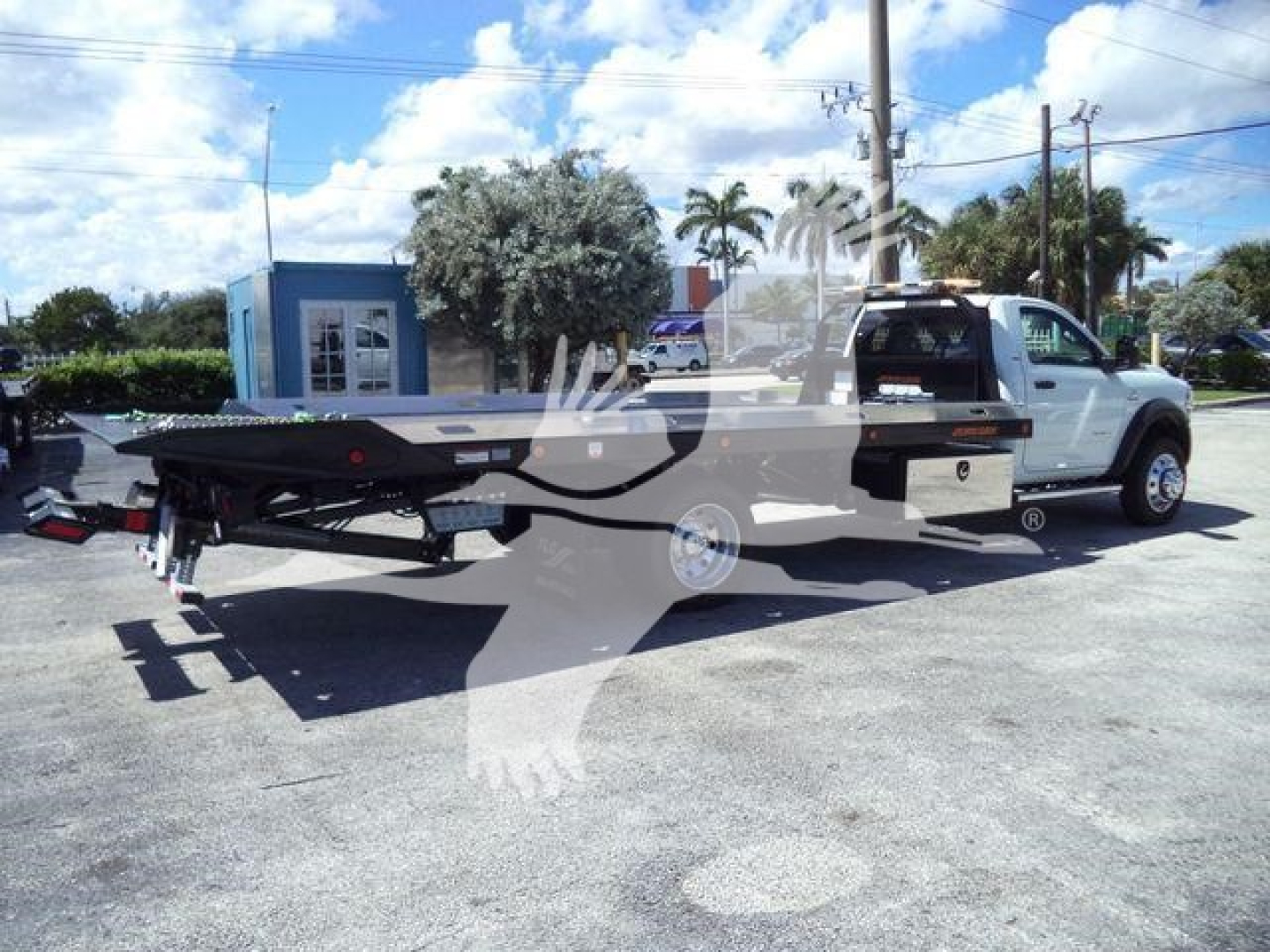 Ram 5500 rollback truck with flatbed seen from rear-left side showing long flatbed and white cab.