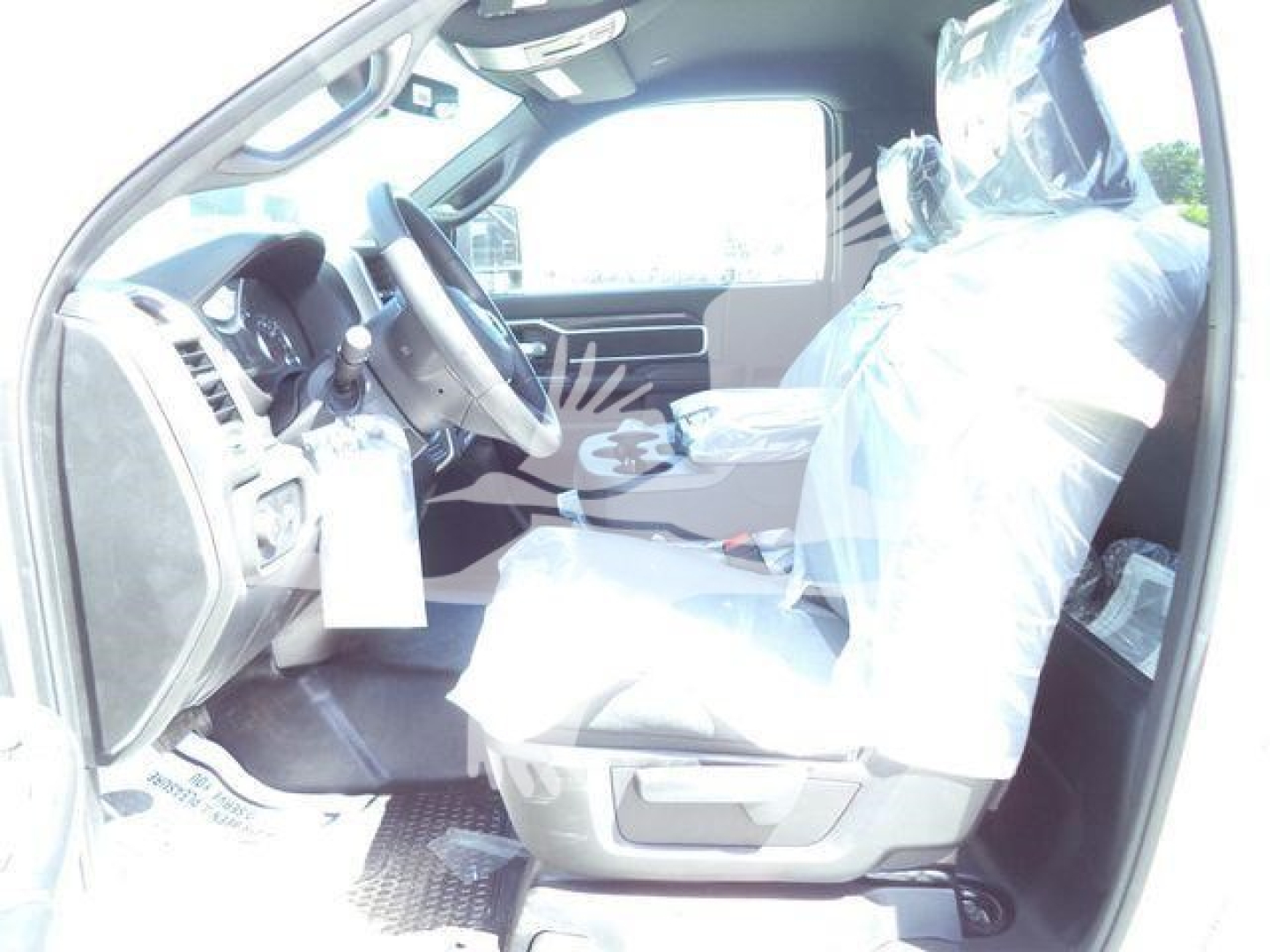 Ram 5500 interior with front seats covered in plastic, steering wheel and dash visible from driver’s side view.