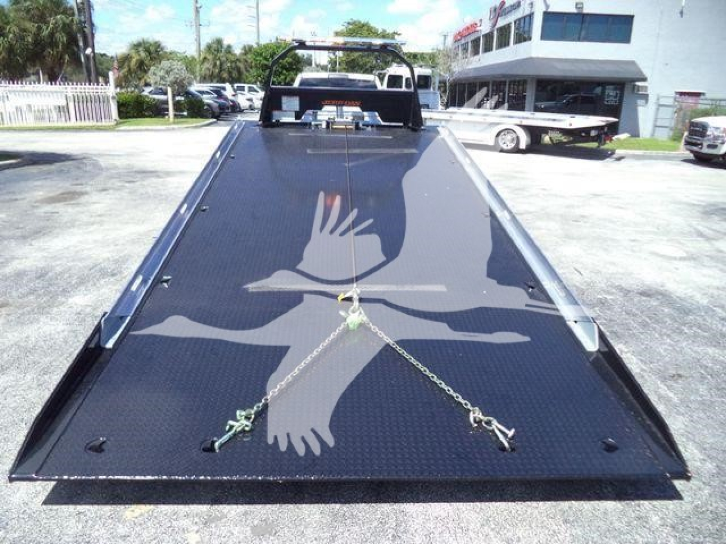 Ram 5500 rollback bed photo showing hydraulic ramps and chain anchors on black diamond plate.