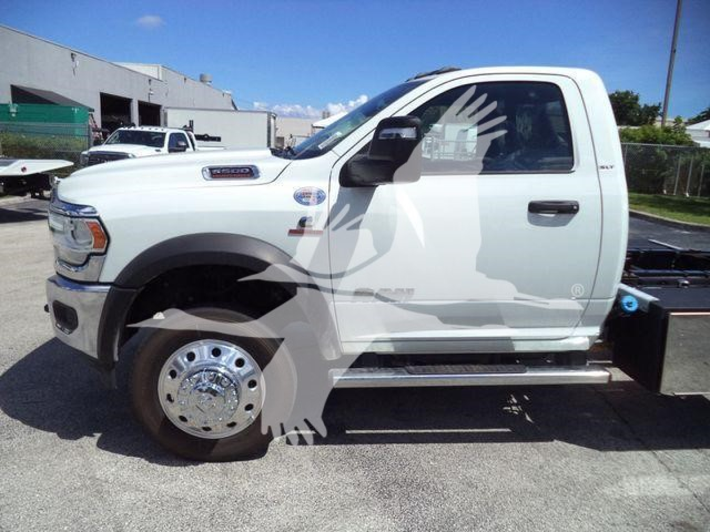 Ram 5500 rollback truck side view showing white cab and chrome wheel covers with side step and black rear bed area.