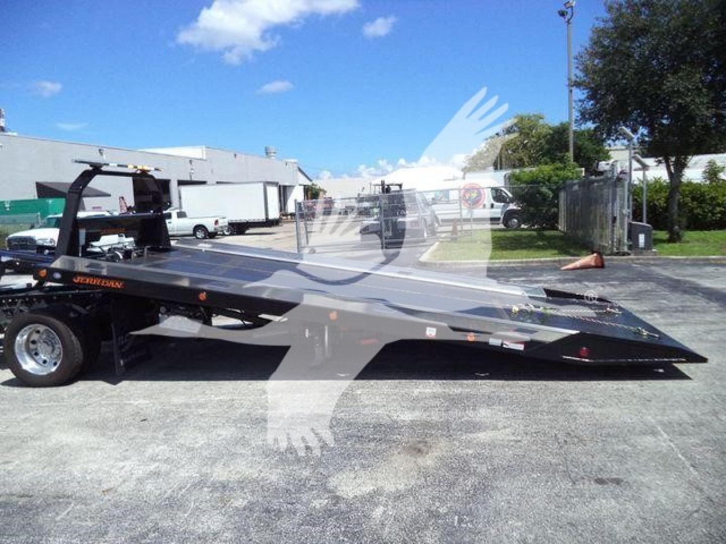 Ram 5500 SLT rollback tow truck low-profile flatbed with hydraulic ramp in a dealership lot.