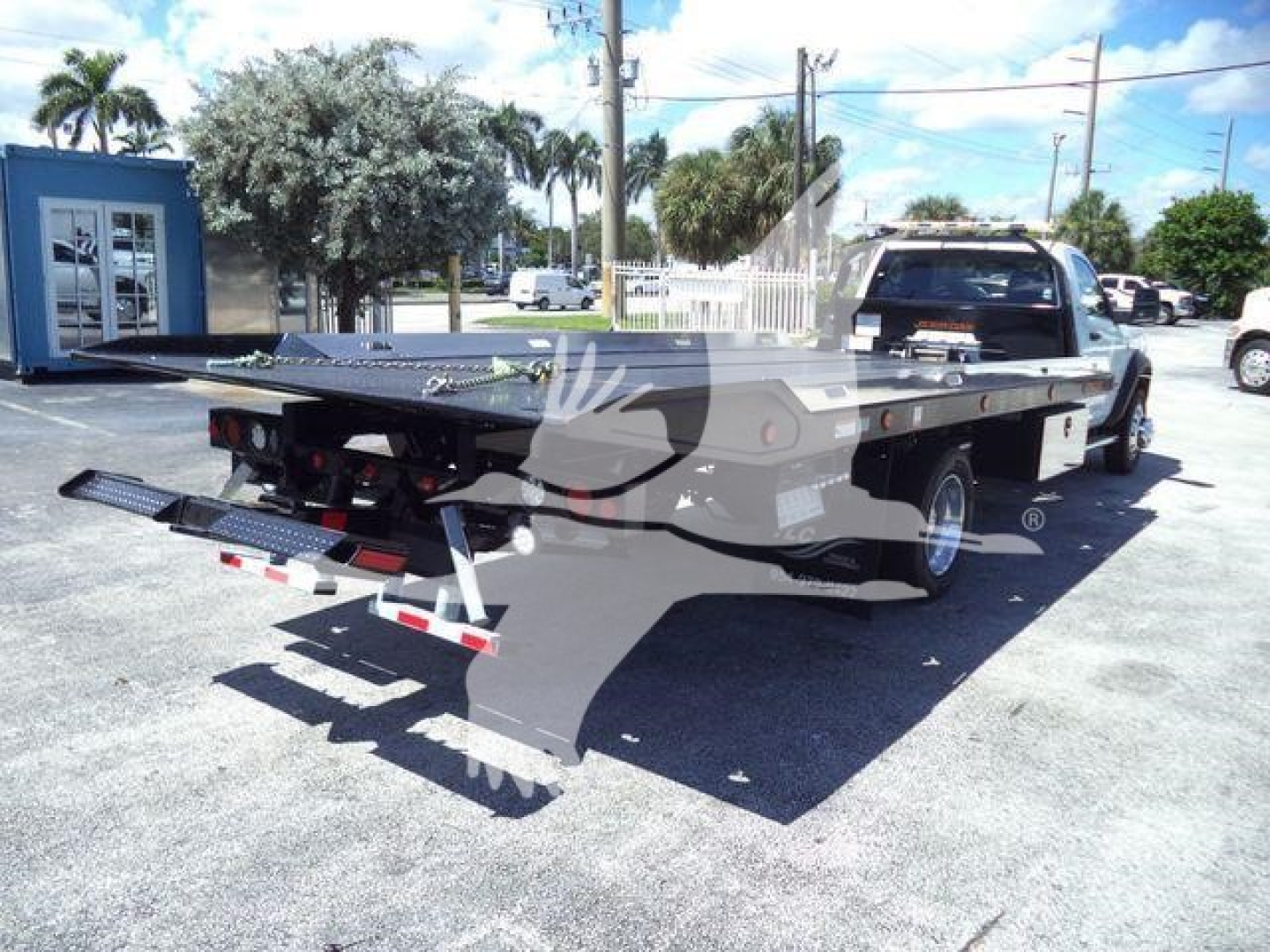 Flatbed tow truck showramp with hydraulic ramps and rear lights attached to a Ram 5500 SLT pickup, side view