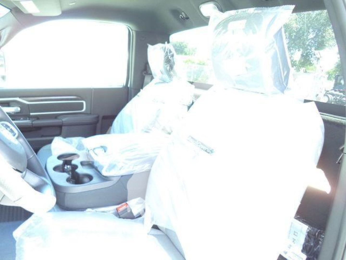 Ram 5500 SLT interior view showing front seats covered in protective plastic and center console with cupholders.