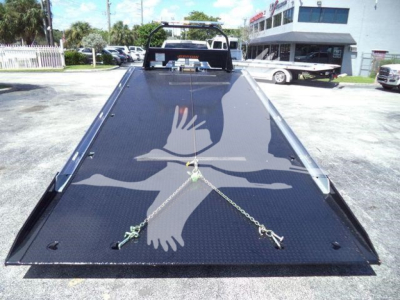 Ram 5500 rollback bed photo showing hydraulic ramps and chain anchors on black diamond plate.