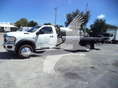 Ram 5500 rollback tow truck in white, side view showing flatbed with dual rear wheels and extended cab.