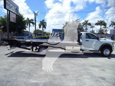 Ram 5500 SLT tow truck/rescue rollback with flatbed on a dealership lot, side view.