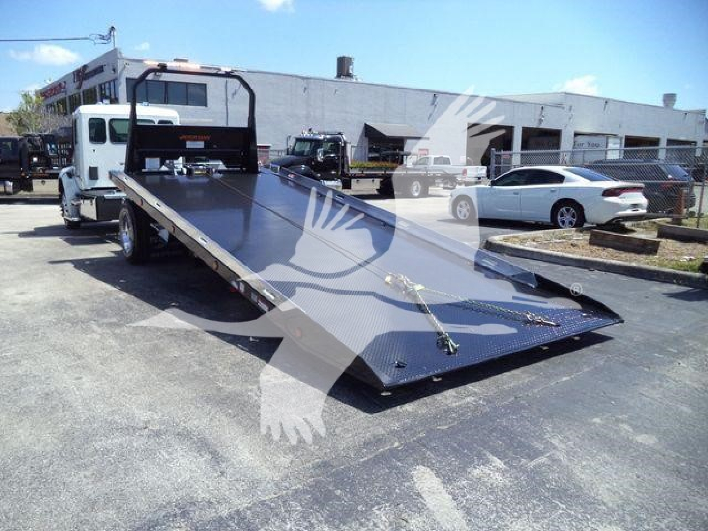 Kenworth T280 rollback truck flatbed in a dealership lot with a large metal loading bed and a white cab, stock number KWT280XLPSHARK visible.