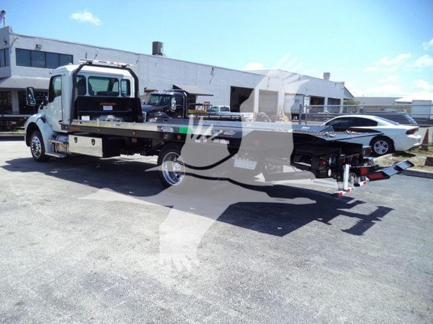 Kenworth T280 rollback tow truck seen from side with flatbed, hydraulic winch, and towing equipment extended.