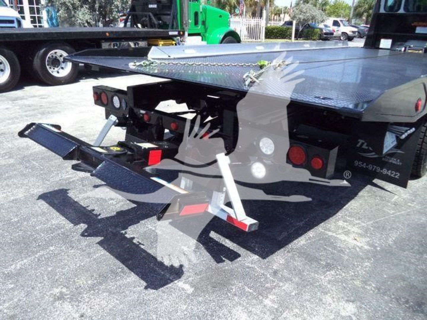 Kenworth T280 rollback truck rear view showing hydraulic tow arms and flatbed with stabilizers.