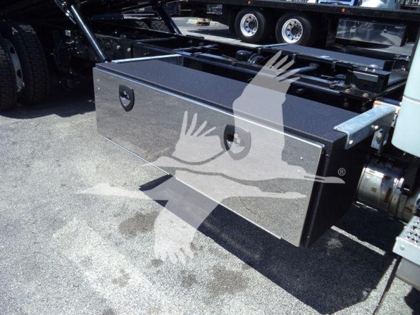 Kenworth T280 rollback truck chassis with a large rectangular toolbox mounted under the frame; chrome latch handles on the toolbox; part of the truck’s frame visible.