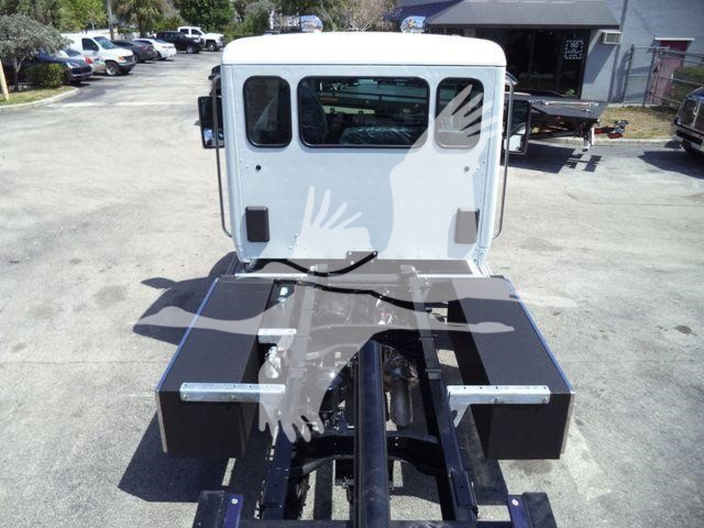 Kenworth T280 rollback truck rear view showing hitch rack and frame components with white cab in background.