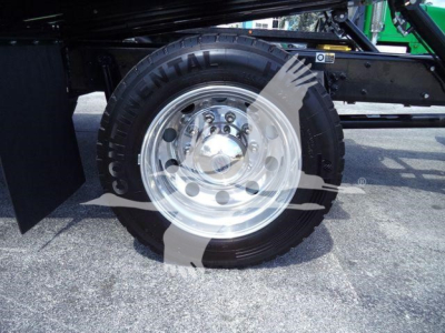 Front wheel and tire of a Kenworth T280 rollback truck showing chrome hub and black tire with visible tread, wheel well and frame components.