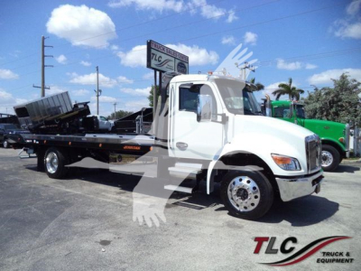Truck and rollback tow truck on lot with white cab and flatbed, Kenworth T280 styling, company signage in background.