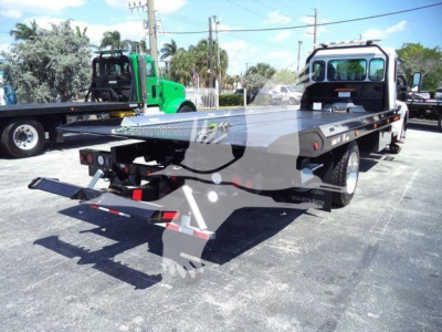 Kenworth T280 rollback truck showing loading ramp and bed with black flatbed and white cab, in-service environment.