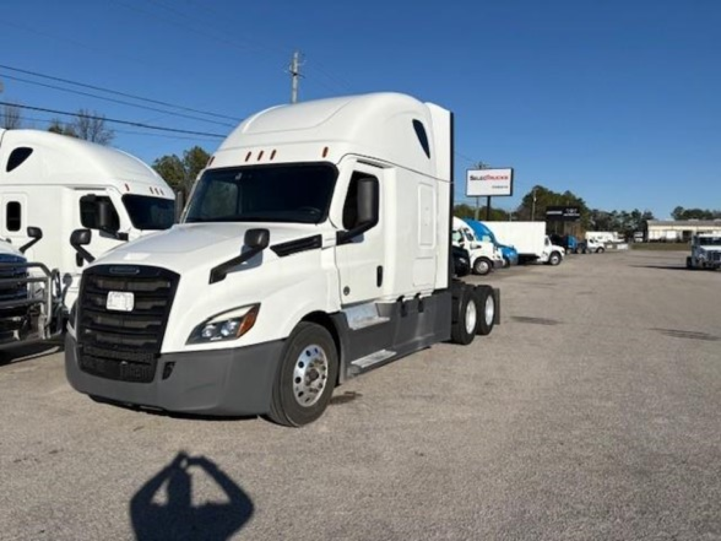 Freightliner Cascadia 126 sleeper truck in a dealership lot, front left view with white cab and sleeper, VIN and stock number not visible on cab.