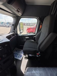 Truck driver seat cockpit view in Freightliner Cascadia 126 interior showing driver's seat and dashboard area.