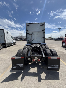 Rear view of 2023 Freightliner Cascadia 126 tractor in a dealership lot showing fifth wheel and dual rear axles with mud flaps.