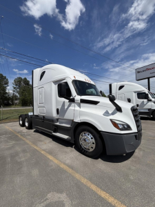 Truck cab with sleeper, 2023 Freightliner Cascadia 126, front left angle, white exterior, chrome wheels, dual rear axles, dealership lot in background.