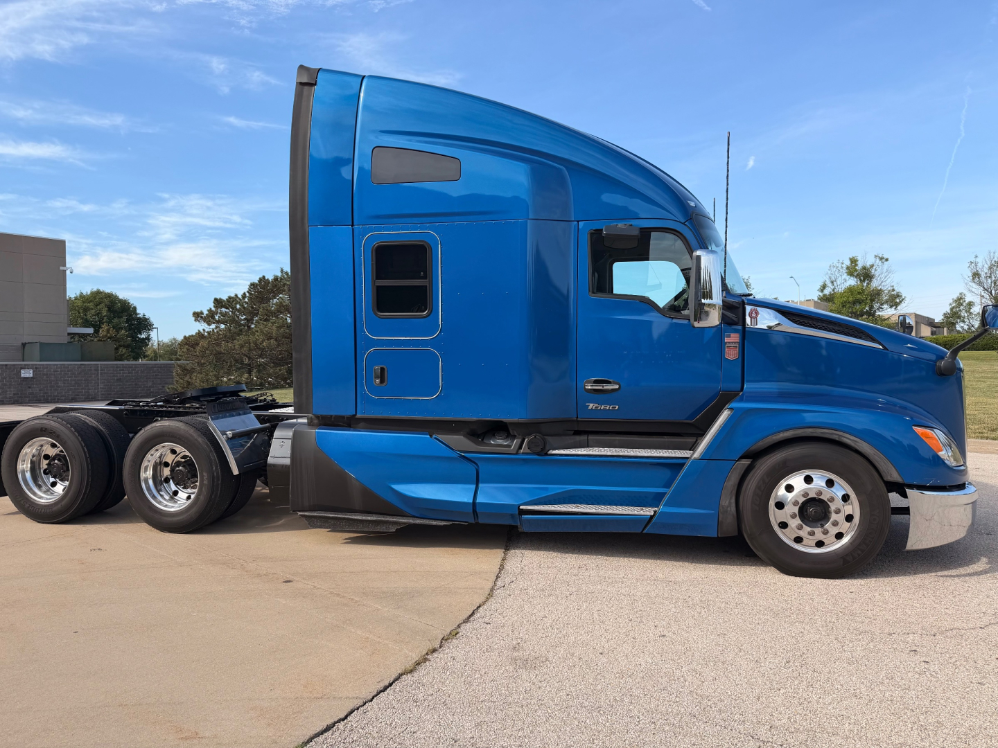 Kenworth T680 conventional sleeper truck side view showing blue cab and wheels