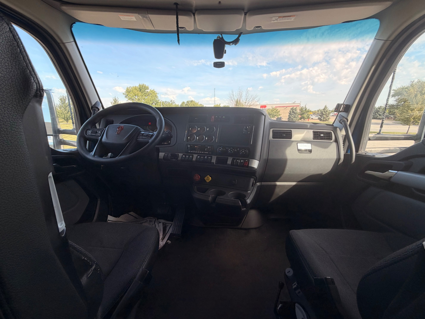 Kenworth T680 cab interior view from driver seat showing dashboard and steering wheel.