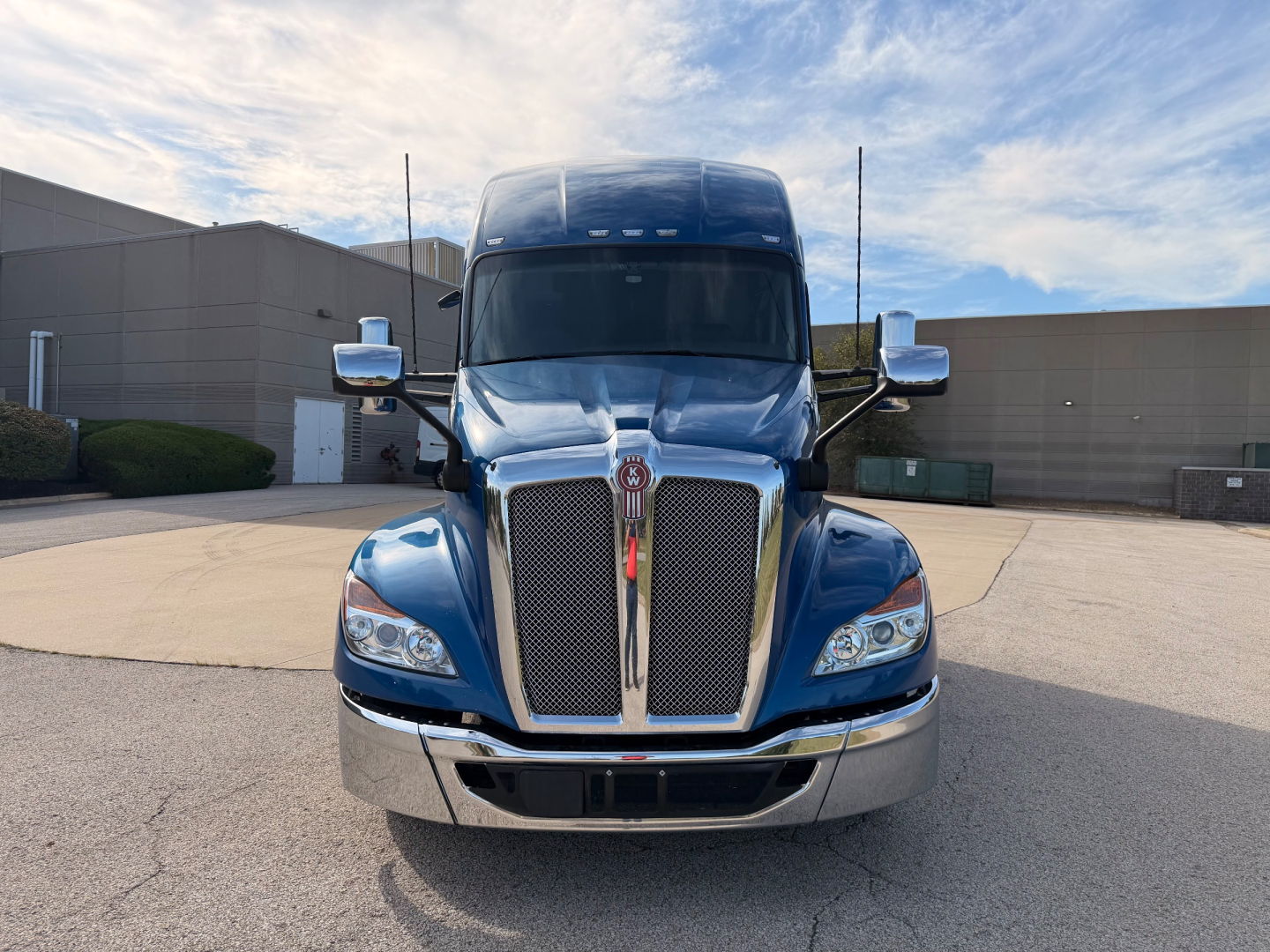 Kenworth T680 truck front view showing chrome grille, blue cab, large windshield, and side mirrors.