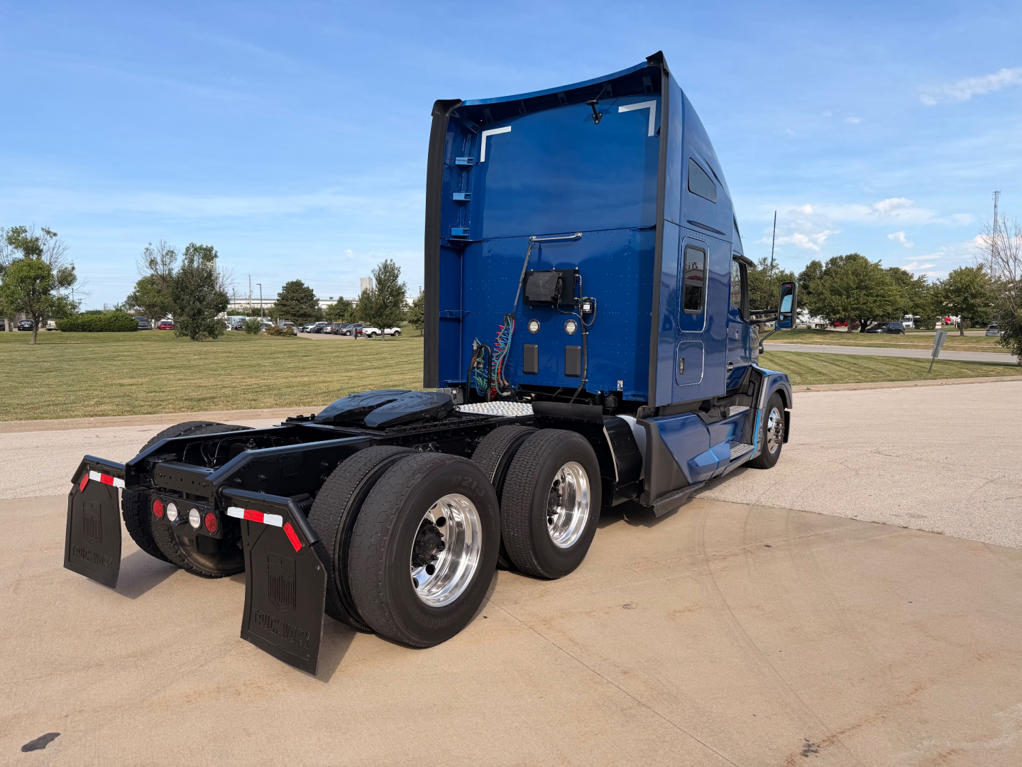 Kenworth T680 tractor in blue, rear view showing sleeper cab, dual rear axles, and fifth wheel.