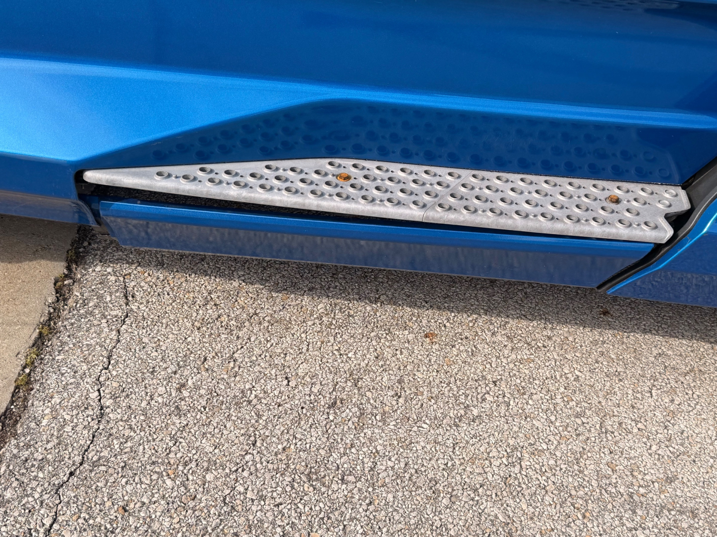 Kenworth T680 side step and blue truck body with textured chrome running board.