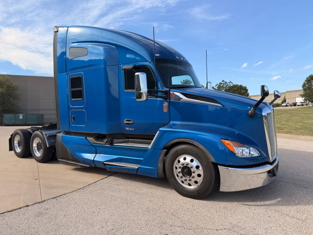Kenworth T680 sleeper cab tractor in blue profile view showing front wheel, side steps, and fuel tanks.