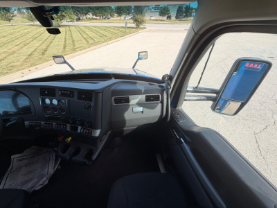 Kenworth T680 interior dashboard and driver-side window view from outside cab, with side mirror and windshield visible.