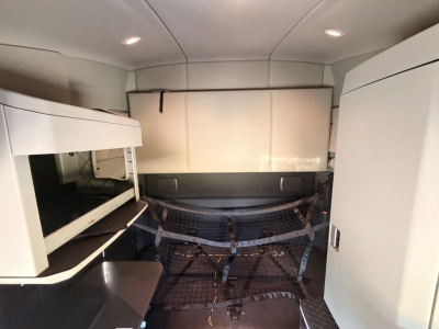 Kenworth T680 sleeper cab interior cargo area with bunk area and netting, inside the cab, clean light gray panels.