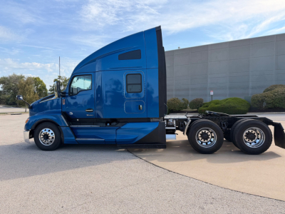 Kenworth T680 tractor unit side view in blue, cab with sleeper, dual rear axles, empty trailer chassis, factory wheels visible.