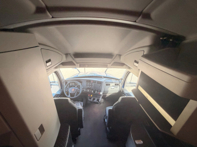 Kenworth T680 cab interior view showing dash and driver seat area, overhead storage and sleeper cab side shelves.