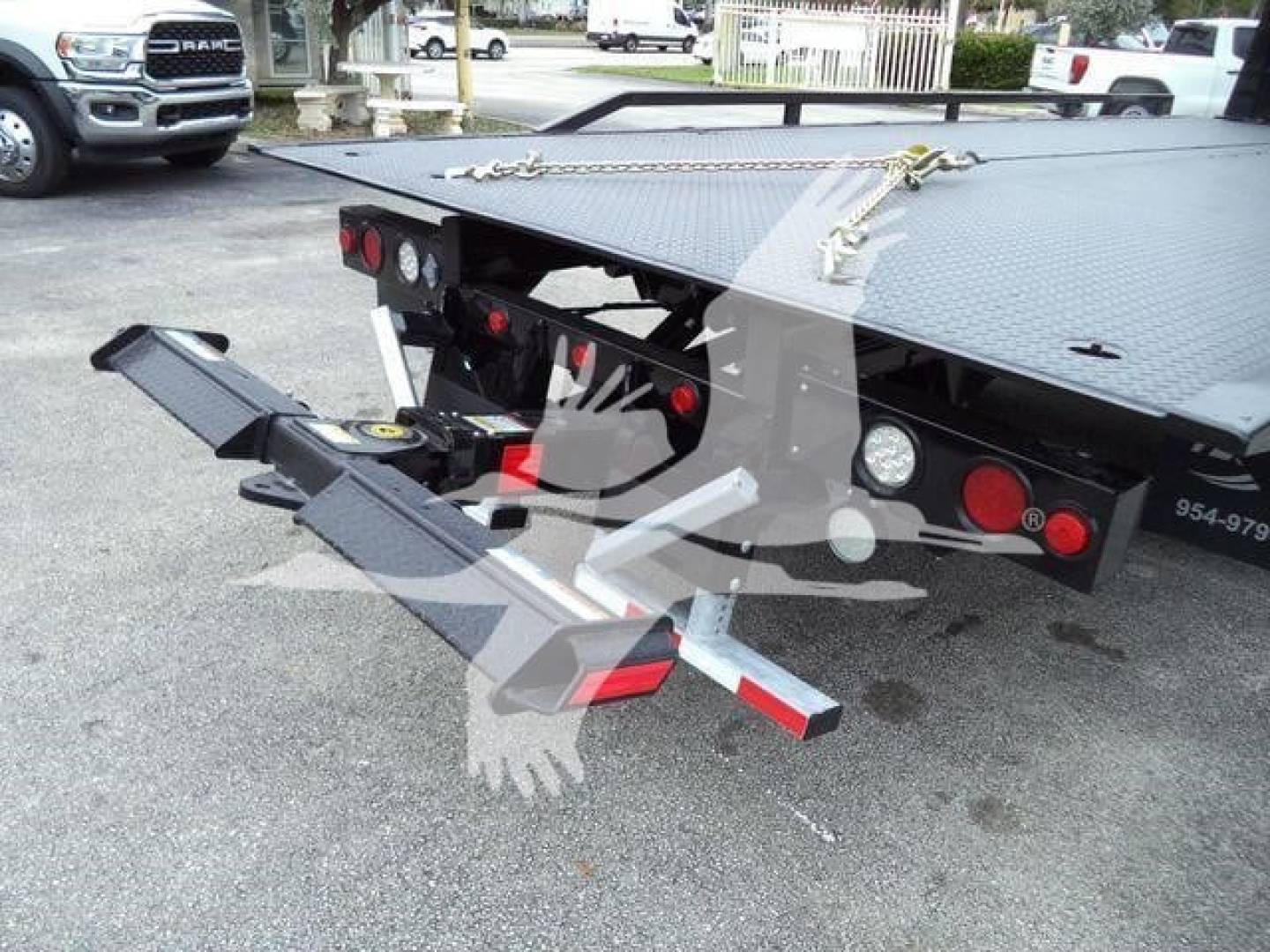 Freightliner M2 106 rollback truck rear with hydraulic tilt bed and chain latching, visible tail lights, and rear bumper steps.