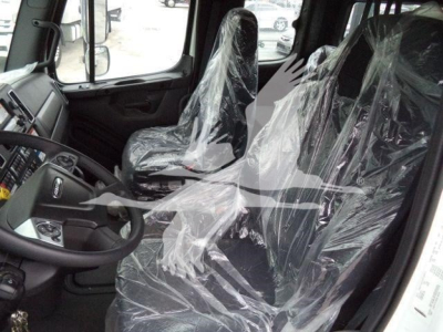 Interior of a new 2027 Freightliner M2 106 truck showing plastic-covered driver and passenger seats and dashboard in the cab.