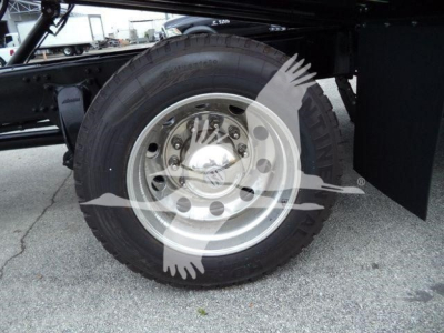 Truck wheel and dual rear axle from Freightliner M2 106 showing steel rim and tire with wheel cover and chassis frame