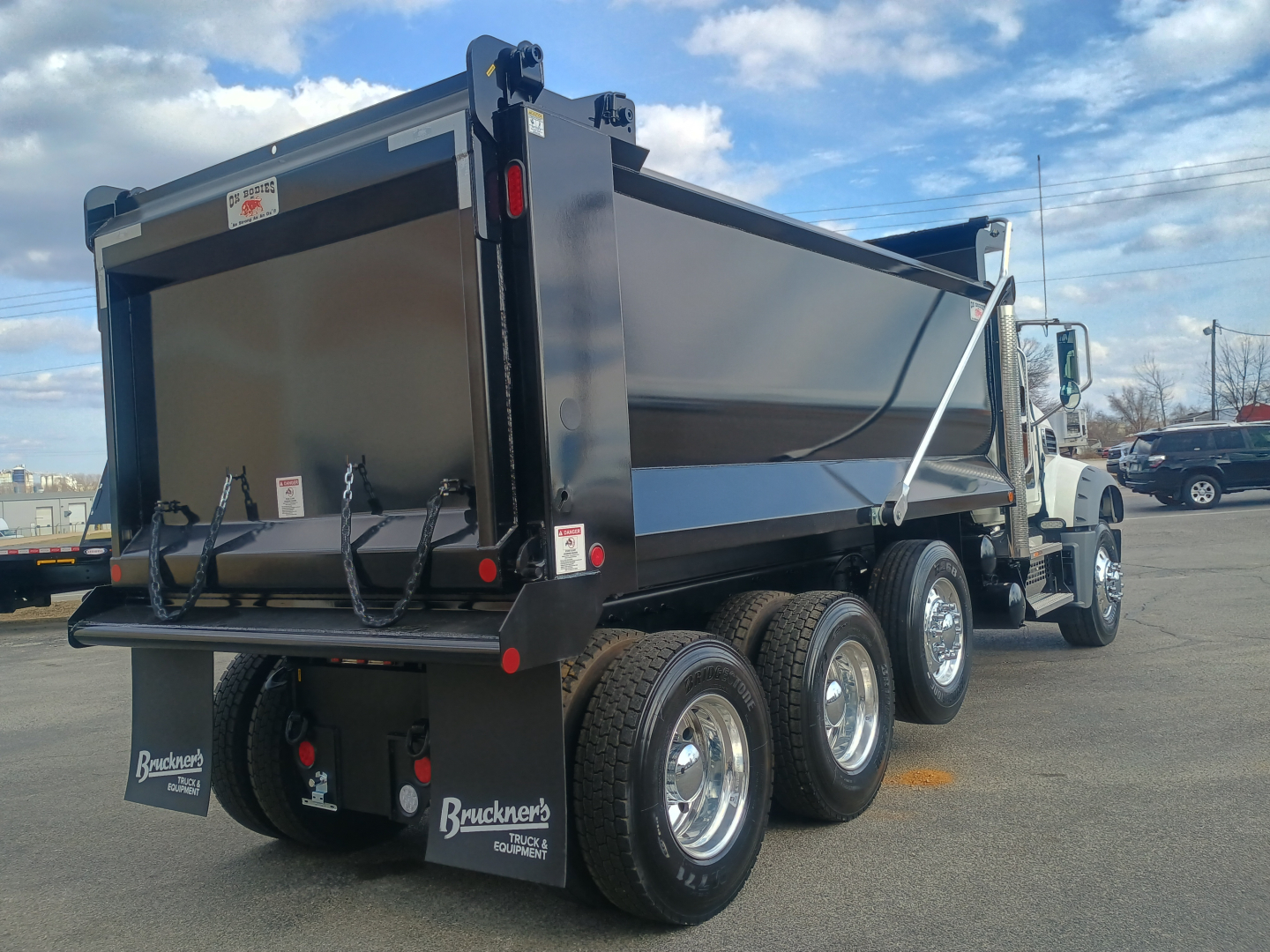 Dump truck rear and side view showing three-axle dual-wheel configuration with a steel dump body, Mack GR84F chassis, and Brancners mud flaps