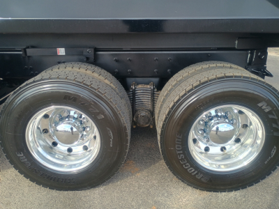 Dual rear wheels of a Mack GR84F dump truck with chrome rims and Bridgestone tires; visible are the inner suspension and axle components.
