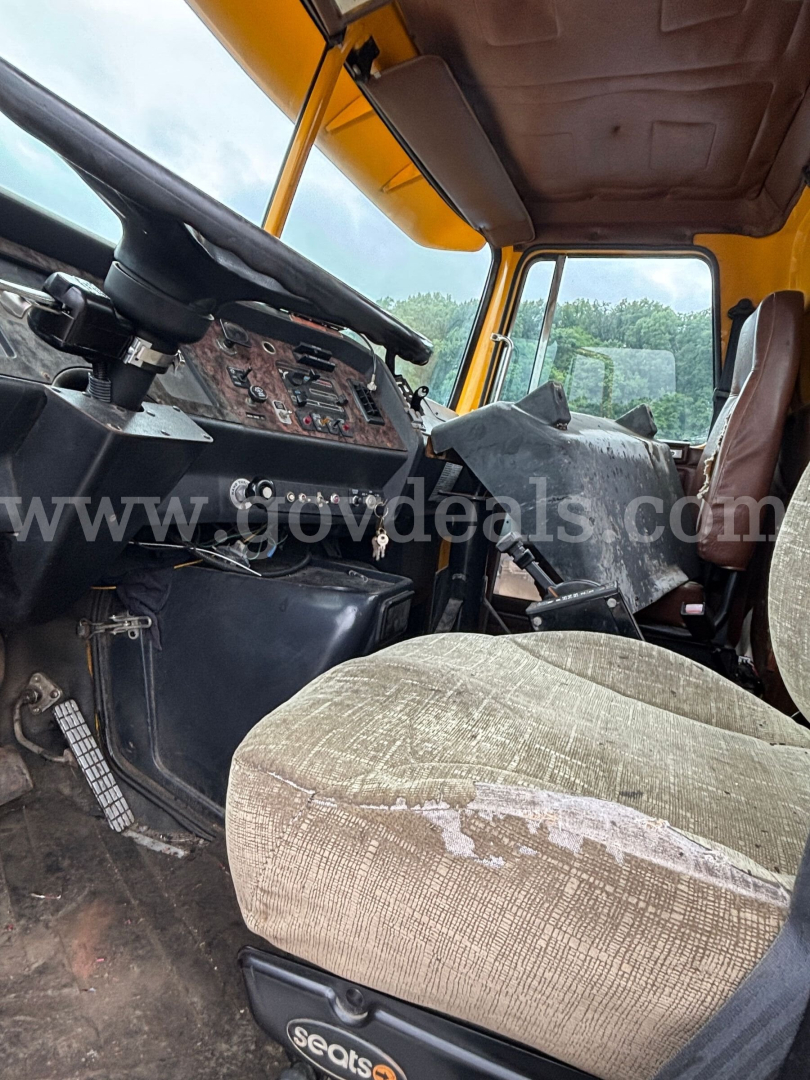 GMC ACL distributor truck cab interior with steering wheel, dashboard controls, and worn fabric seat in view.