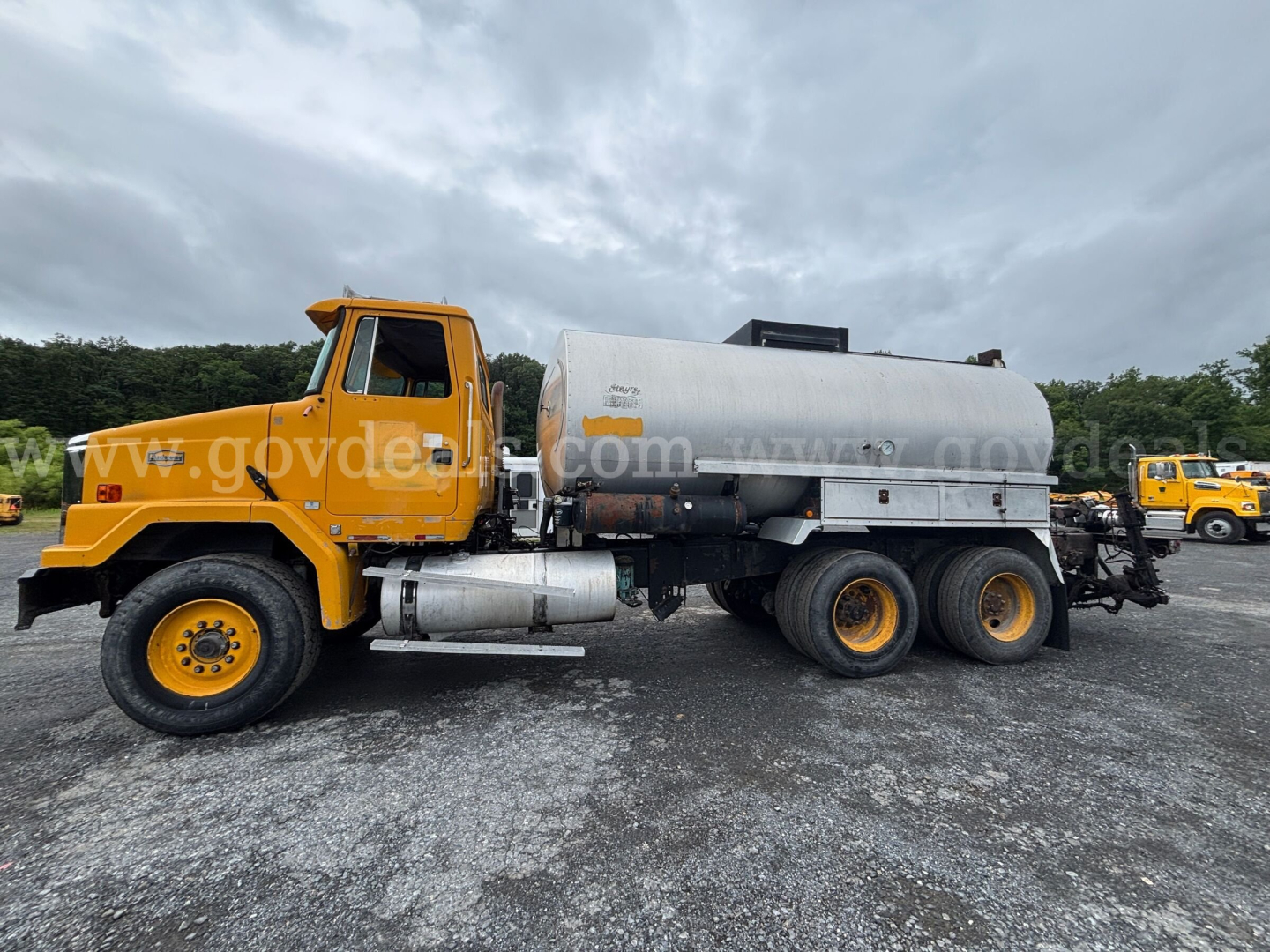 GMC ACL distributor truck in orange with a large cylindrical tank, side profile view showing front cab and dual rear axles.