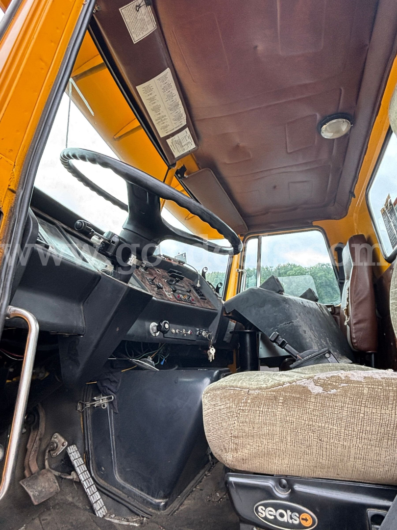 GMC ACL distributor truck interior with steering wheel, dashboard, and worn seat in a dusty operator cabin.