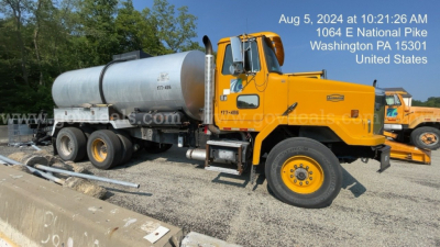 GMC ACL distributor truck with a large cylindrical tank mounted on a yellow cab and dual rear wheels; VIN visible on plate; date stamp and location overlay.