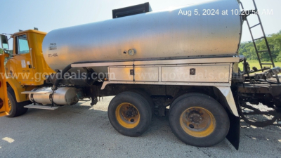 GMC ACL distributor truck with a cylindrical stainless tank, dual rear wheels, and a yellow cab visible on the left; side toolbox and piping along the tank; date stamp in top right.