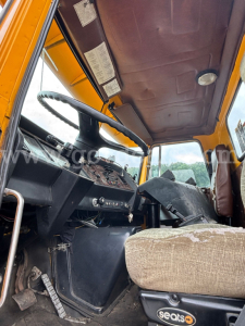 GMC ACL distributor truck interior with steering wheel, dashboard, and worn seat in a dusty operator cabin.