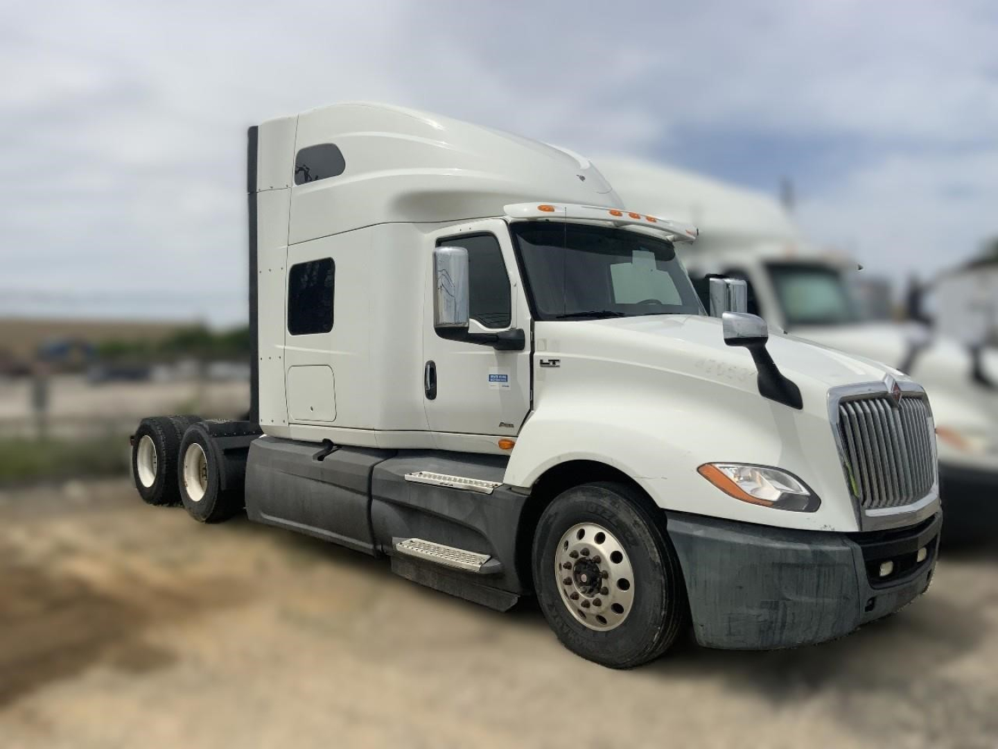 International LT cab and front axle tractor showing sleeper cab, white paint, front grille, side mirrors, and 6-wheel rear with dual axles.